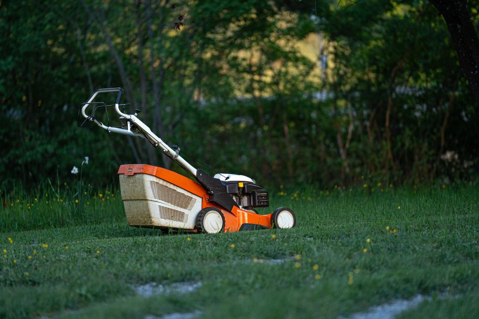 Professional pushing a commercial lawn mower across a large yard